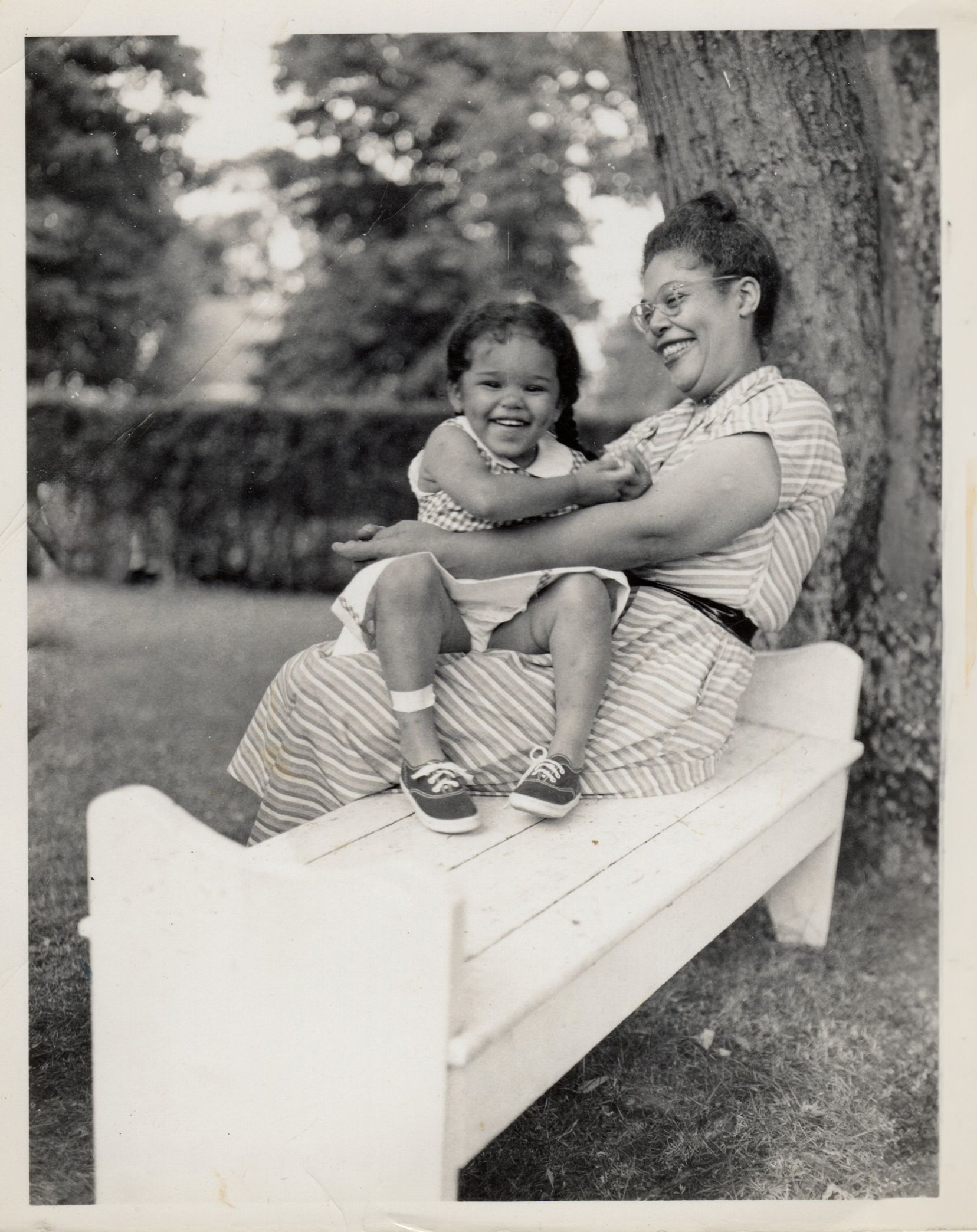 Ann Petry, sitting in a bench beneath a tree, with her daughter, Liz on her lap. Image courtesy of Ashley James.